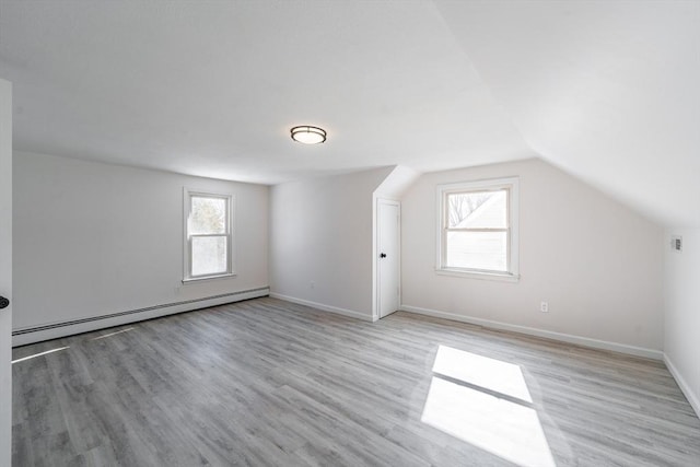 additional living space with lofted ceiling, plenty of natural light, light wood-style flooring, and baseboard heating