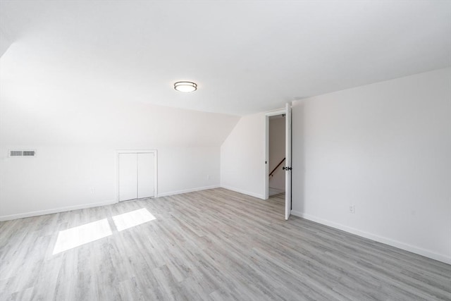 bonus room with lofted ceiling, light wood-style floors, baseboards, and visible vents