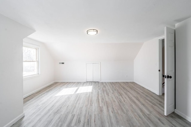 bonus room with baseboards, vaulted ceiling, and light wood-style floors