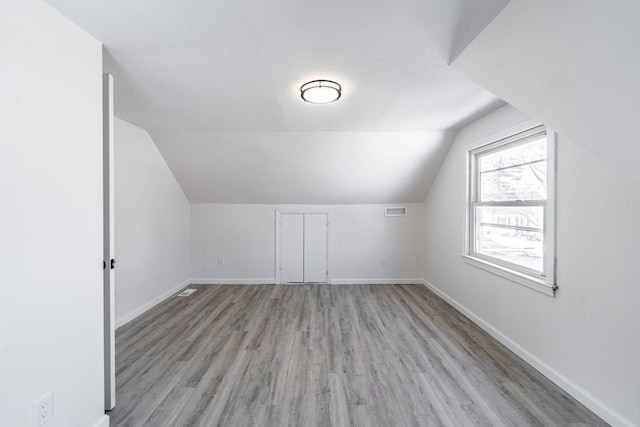 additional living space featuring light wood-type flooring, visible vents, and baseboards