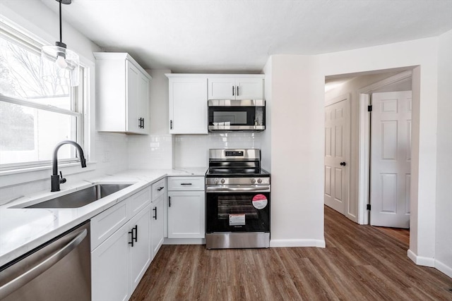 kitchen featuring white cabinetry, stainless steel appliances, a sink, and pendant lighting