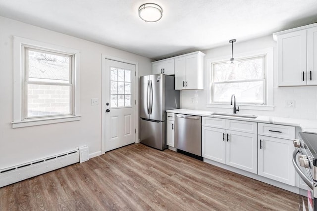 kitchen featuring a baseboard heating unit, light countertops, appliances with stainless steel finishes, and white cabinets