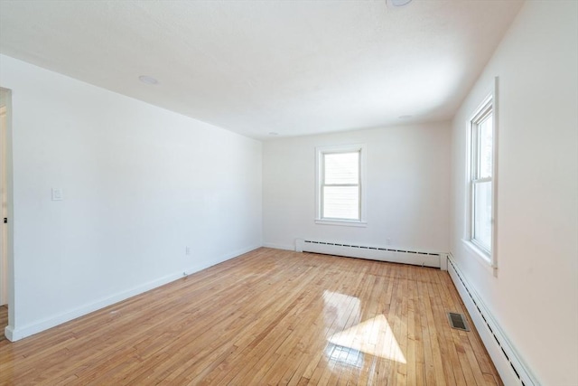 empty room with baseboards, a baseboard radiator, and light wood-style floors