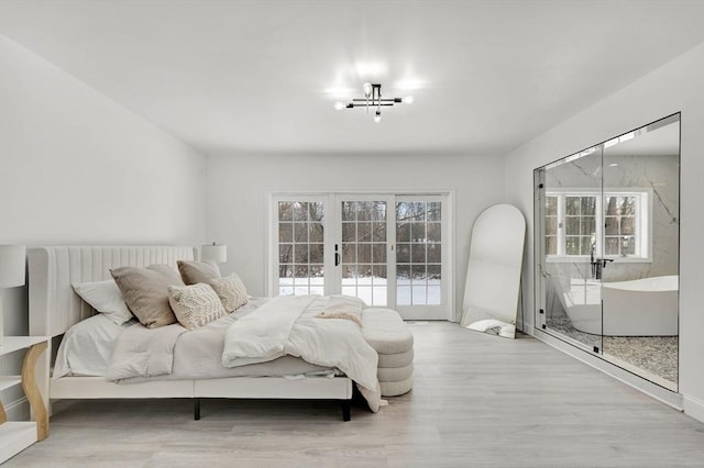 bedroom with access to exterior, light wood-type flooring, and french doors