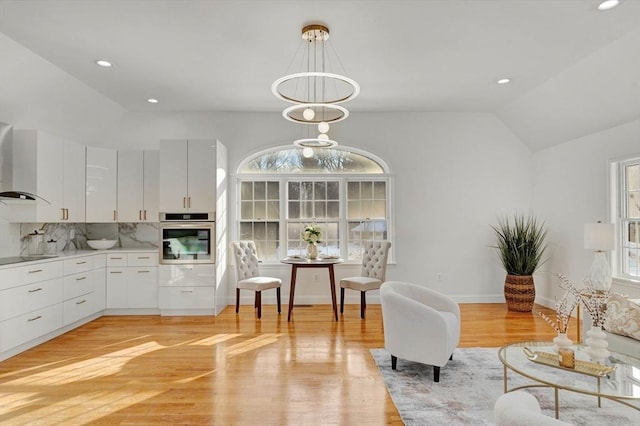 sitting room featuring an inviting chandelier, vaulted ceiling, and light hardwood / wood-style floors