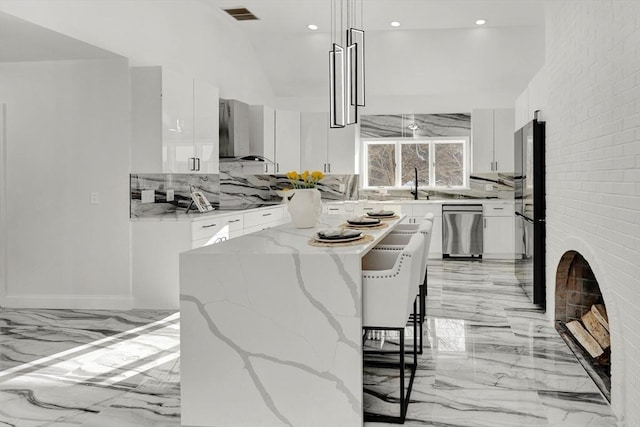 kitchen with pendant lighting, dishwasher, white cabinetry, a center island, and wall chimney exhaust hood