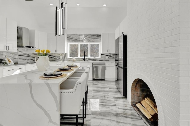 kitchen with wall chimney exhaust hood, a kitchen bar, white cabinetry, light stone counters, and pendant lighting