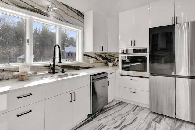 kitchen featuring sink, light stone countertops, white cabinets, and appliances with stainless steel finishes