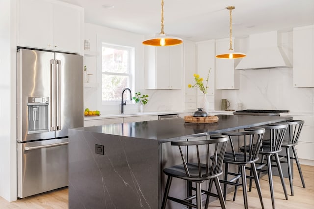 kitchen with high end fridge, white cabinets, a kitchen island, and custom exhaust hood