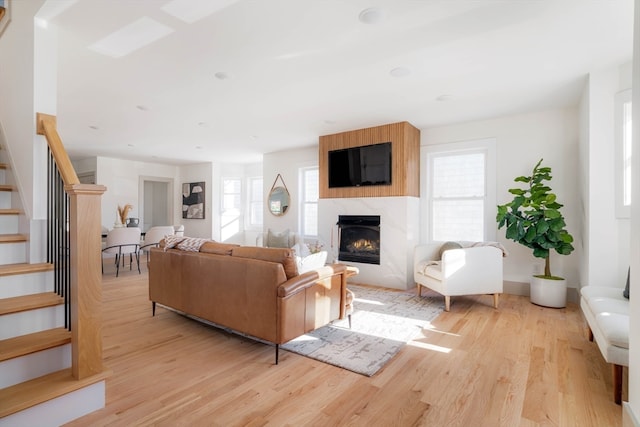 living room with a high end fireplace and light hardwood / wood-style floors