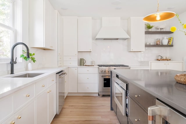 kitchen with premium range hood, hanging light fixtures, sink, appliances with stainless steel finishes, and white cabinetry