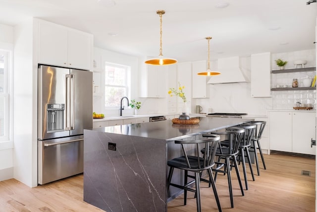 kitchen with premium range hood, white cabinets, a kitchen island, and appliances with stainless steel finishes