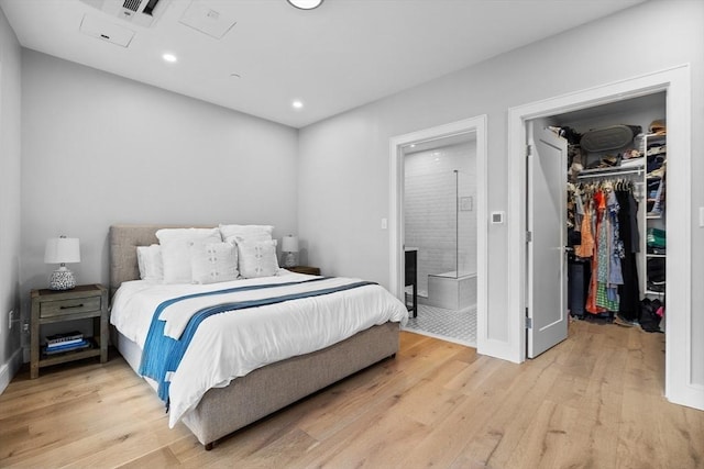 bedroom with visible vents, ensuite bath, light wood-style flooring, a closet, and a walk in closet