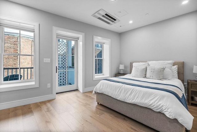 bedroom with multiple windows, light wood-style flooring, baseboards, and access to outside