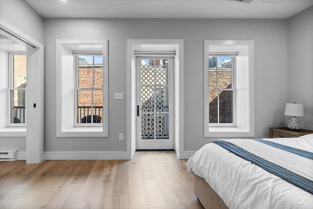 bedroom featuring access to outside, multiple windows, baseboards, and light wood-type flooring