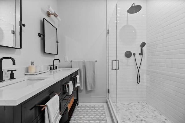 bathroom featuring a sink, baseboards, a stall shower, and double vanity