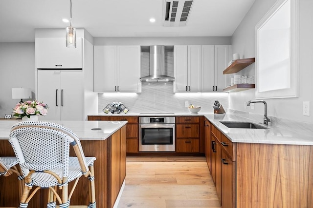 kitchen featuring visible vents, open shelves, a sink, wall chimney range hood, and stainless steel oven