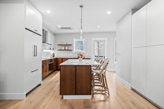 kitchen featuring a breakfast bar, open shelves, white cabinets, light countertops, and stainless steel oven