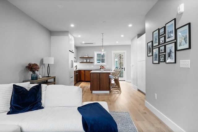 living area with recessed lighting, baseboards, and light wood-style flooring