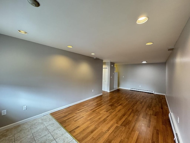 empty room with baseboards, baseboard heating, and wood finished floors