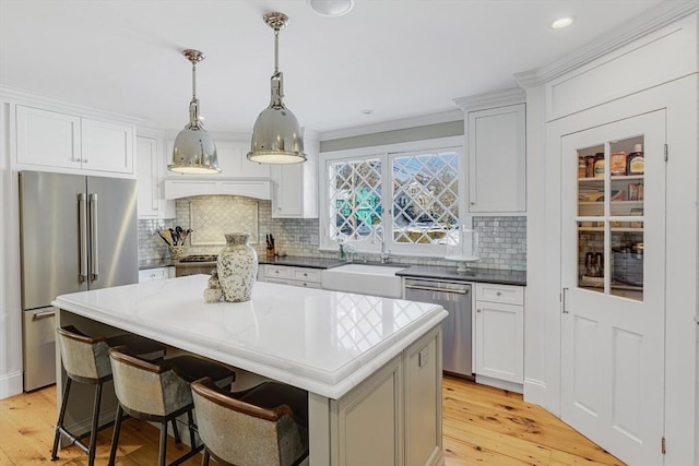 kitchen with pendant lighting, sink, appliances with stainless steel finishes, a center island, and a kitchen bar