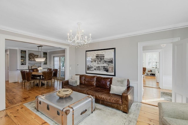 living room featuring ornamental molding, a chandelier, and light hardwood / wood-style flooring