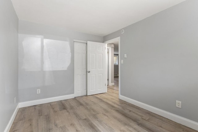 unfurnished bedroom with baseboards, wood finished floors, and a closet