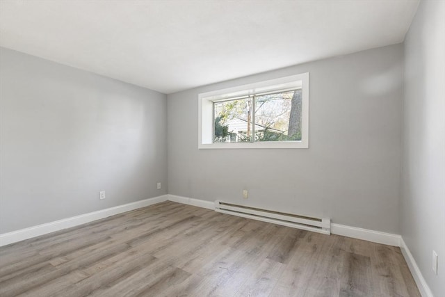 spare room featuring baseboard heating, wood finished floors, and baseboards
