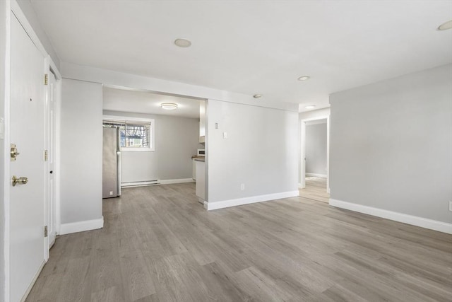 basement with freestanding refrigerator, light wood-style flooring, baseboards, and recessed lighting