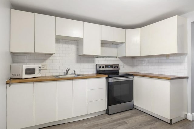kitchen with stainless steel electric range, white microwave, a sink, and wood counters