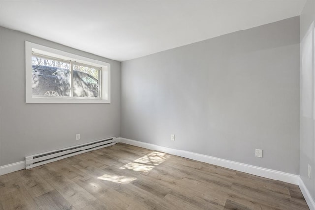 empty room featuring a baseboard radiator, wood finished floors, and baseboards