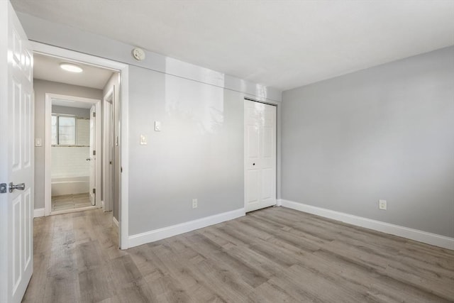 spare room with light wood-style flooring, baseboards, and a smoke detector
