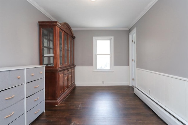 spare room featuring dark hardwood / wood-style floors, baseboard heating, and crown molding