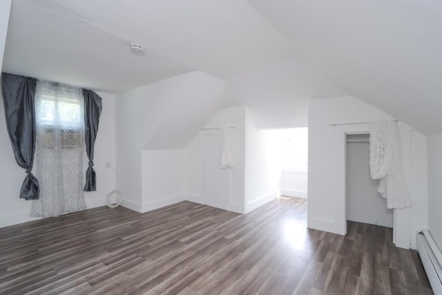 additional living space with dark hardwood / wood-style floors, baseboard heating, and vaulted ceiling