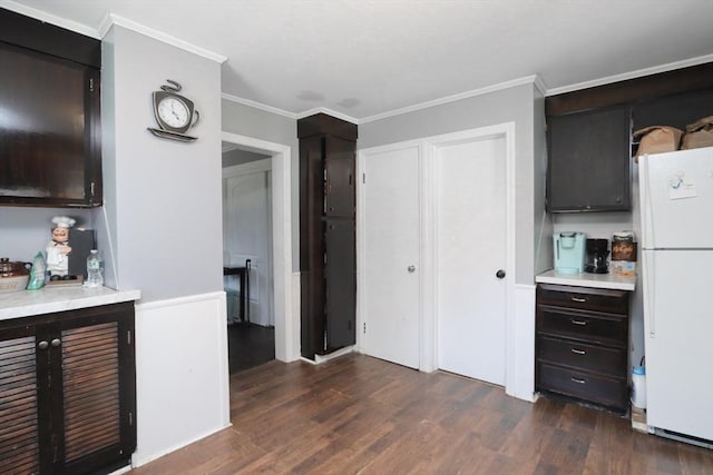 kitchen featuring dark hardwood / wood-style floors, white refrigerator, dark brown cabinets, and ornamental molding