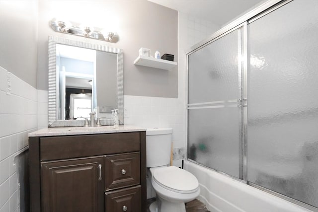 full bathroom with vanity, toilet, enclosed tub / shower combo, and tile walls