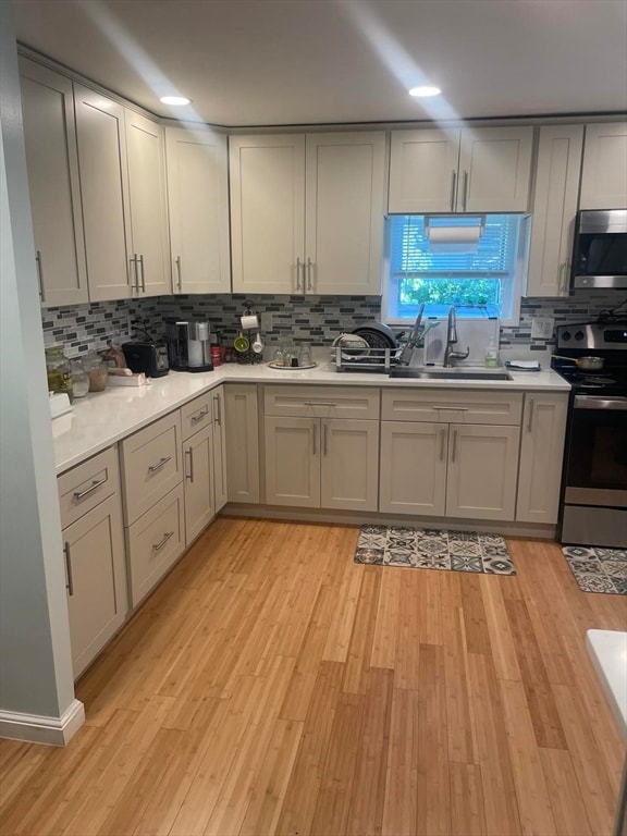 kitchen with sink, tasteful backsplash, light hardwood / wood-style flooring, and stainless steel appliances