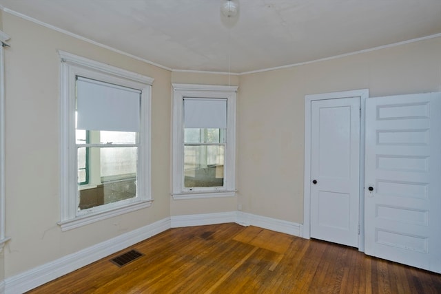 empty room featuring dark hardwood / wood-style flooring and ornamental molding