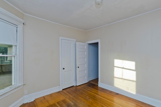 unfurnished bedroom featuring crown molding, a closet, and wood-type flooring