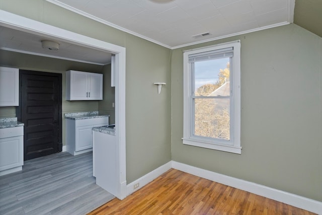 interior space with white cabinets, light wood-type flooring, and crown molding