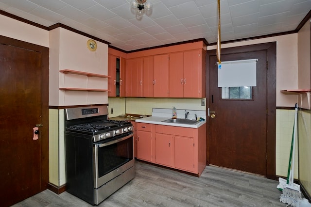 kitchen with stainless steel gas range oven, sink, ornamental molding, and light wood-type flooring