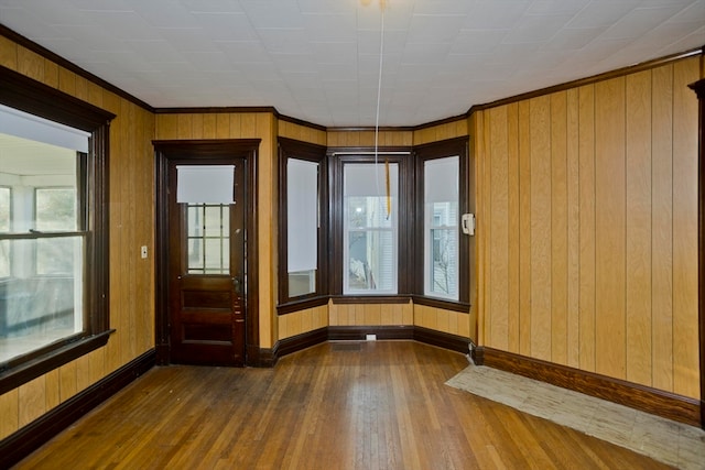 interior space with ornamental molding, dark wood-type flooring, and wood walls