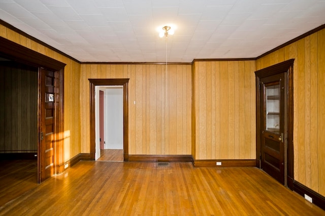 unfurnished room with hardwood / wood-style floors and wood walls