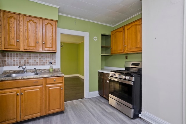 kitchen with sink, stainless steel gas stove, light wood-type flooring, ornamental molding, and tasteful backsplash