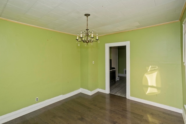 spare room with dark hardwood / wood-style flooring, an inviting chandelier, and ornamental molding