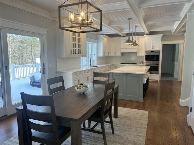 interior space featuring double oven, a sink, cooktop, coffered ceiling, and plenty of natural light