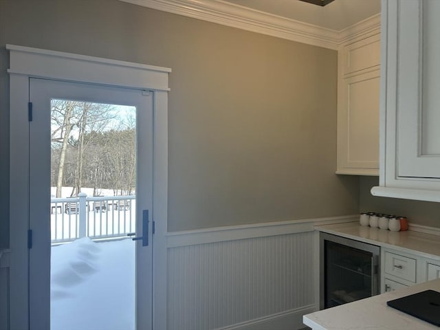interior space with crown molding, light countertops, white cabinetry, and wainscoting