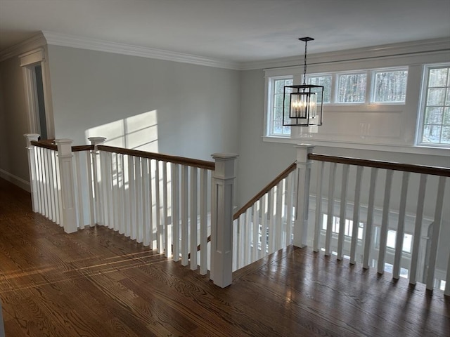 staircase with a chandelier, ornamental molding, and wood finished floors