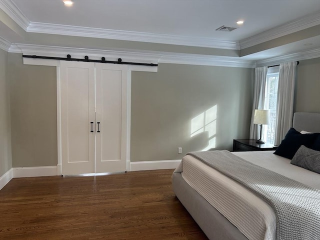 bedroom featuring dark wood-type flooring, baseboards, ornamental molding, and a barn door