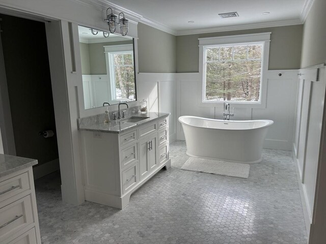 bathroom with a soaking tub, a decorative wall, ornamental molding, visible vents, and a wainscoted wall